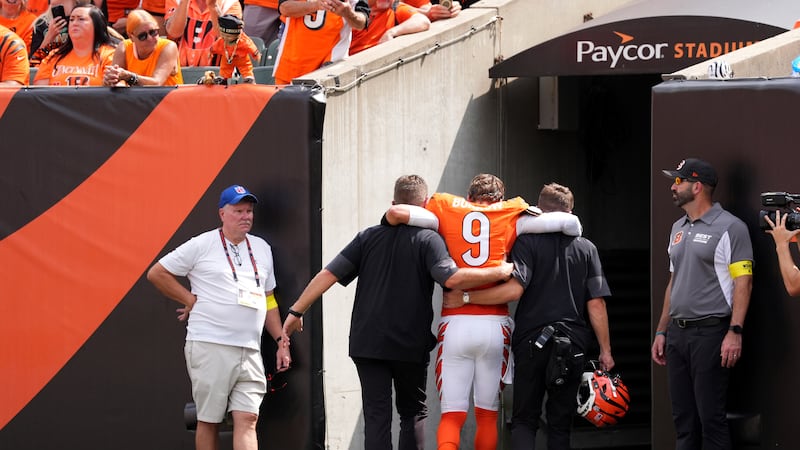 Cincinnati Bengals quarterback Joe Burrow, center, is helped off the field after suffering an...